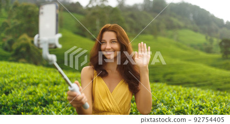 Asian vlogger traveler woman making selfie on mobile phone camera share via app her travel vacation to famous nature landmark tea plantations in Sri Lanka. 92754405