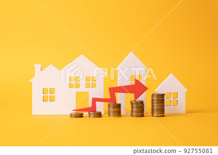 Coins on a table, a red up arrow and house. The concept of the rising price of real estate 92755081