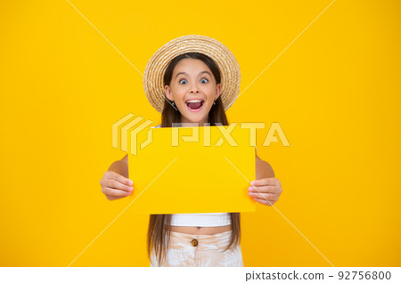 surprised teen girl hold empty advertisement paper with copy space on yellow background 92756800