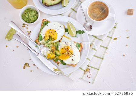 healthy breakfast or snack - sliced avocado and fried egg on toasted bread and cup of coffee 92756980