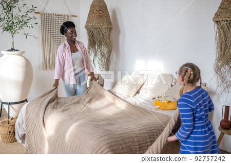 A woman and a girl making bed in the morning A woman and a girl making bed in the morning 92757242