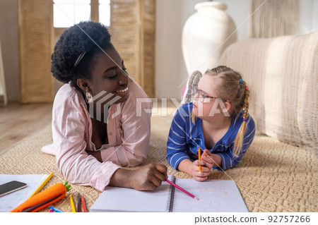 A girl in eyeglasses looking at her teacher whule studying at home A girl in eyeglasses looking at her teacher whule studying at home 92757266