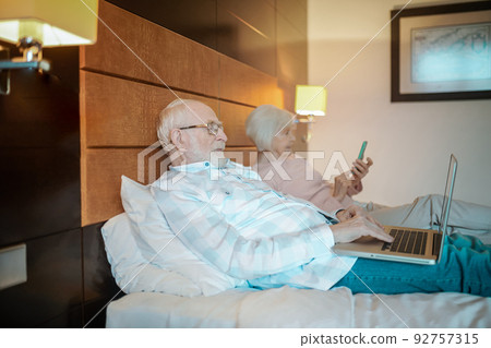 Senior couple lying in bed and watching something online 92757315