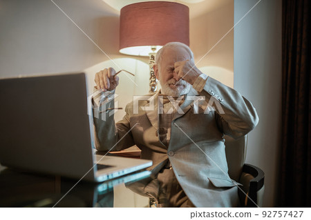 Senior man sitting at the laptop and looking tired Senior man sitting at the laptop and looking tired 92757427