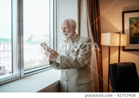 Elegant man in a suit looking at the smartphone with anticipation 92757436