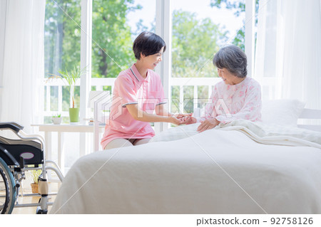 Nursing Caregiver helping seniors getting up from bed 92758126