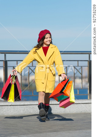 Time to shop. Shopping day. happy little girl. Autumn trend. Kid fashion look. little girl with shopping bags. Spring sales. Stylish child in french beret and fall coat. Clothing shop. Shop tradition 92758209