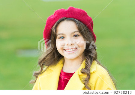 Fashionable girl curly hair on sunny autumn day close up. Stunning charisma. Girl adorable kid walk defocused background. Kid bright hat and warm coat. Adorable face. Adorable baby fashion model 92758213