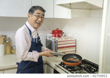 A man in his 70s grilling steak 92759952
