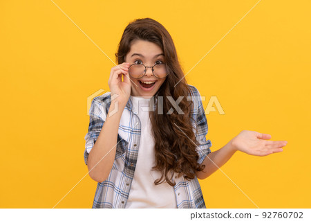 surprised teen kid in checkered shirt and glasses on yellow background 92760702