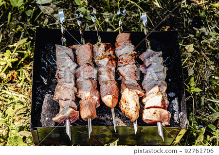 Burnt pork skewers on iron grill, outdoors, close-up, over real charcoal. 92761706
