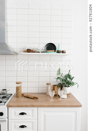 Bright kitchen in the Scandinavian style. Pasta in a glass jar, houseplant, glasses and kitchen utensils 92761804