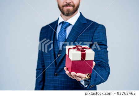 Having outside that looks as good as inside. Wrapped box in male hand. Box tied with ribbon. Gift shop. Present delivery. Boxing day. Holiday celebration. Businessman cropped view 92762462