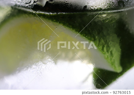 一個玻璃的特寫鏡頭與充分冷卻的酒和石灰。玻璃表面的霜給人一種清爽的感覺。 92763015
