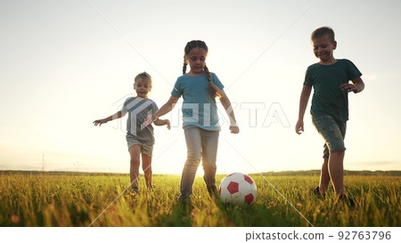 children in the park. happy group of children playing ball in the summer on the grass in the park sunset glare. happy family soccer kid dream concept. sun a group of children playing ball in the park children in the park. happy group of children playing ball in the summer on the grass in the park sunset glare. happy family soccer kid dream concept. sun a group of children playing ball in the park 92763796