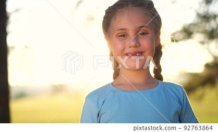 portrait of a little girl in the park. close-up of a girl in nature. happy family child concept. happy girl smiling. cheerful close-up portrait of a little girl. child sunshine outdoors in the park portrait of a little girl in the park. close-up of a girl in nature. happy family child concept. happy girl smiling. cheerful close-up portrait of a little girl. child sunshine outdoors in the park 92763864