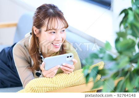 便衣的年輕女人，客廳，智能手機 92764148