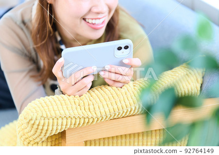 便衣的年輕女人，客廳，智能手機 92764149