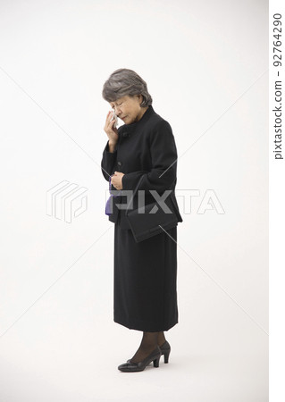 Senior woman in mourning clothes wiping tears with a handkerchief 92764290