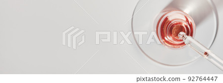 Oil or Serum bottle and pipette in petri dish on grey banner. Pink cosmetic product 92764447