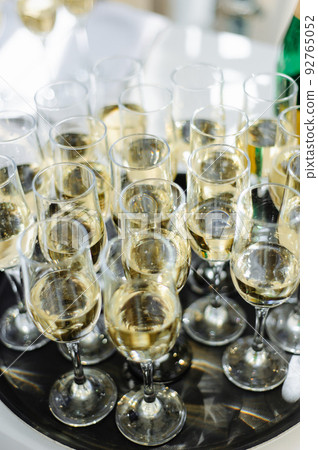 A lot of wine glasses with a cool delicious champagne or white wine at the bar. Alcohol background. A lot of wine glasses with a cool delicious champagne or white wine at the bar. Alcohol background. 92765052