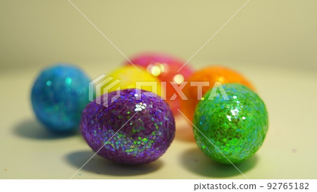 Colorful Easter eggs rotating in rows in a seamless loop on a light background Colorful Easter eggs rotating in rows in a seamless loop on a light background 92765182