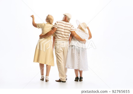 Handsome senior man and two charming women in vintage retro style outfits isolated on white background. Concept of 60s, 70s, american fashion style Handsome senior man and two charming women in vintage retro style outfits isolated on white background. Concept of 60s, 70s, american fashion style 92765655