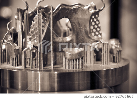 Object printed on metal 3d printer close-up. Object printed in laser sintering machine. Modern 3D printer printing from metal powder. Concept progressive additive DMLS, SLM, SLS 3d printing technology Object printed on metal 3d printer close-up. Object printed in laser sintering machine. Modern 3D printer printing from metal powder. Concept progressive additive DMLS, SLM, SLS 3d printing technology 92765665