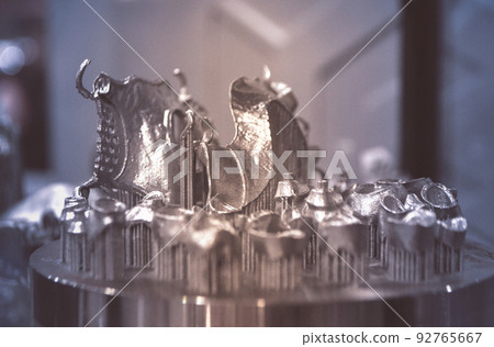 Object printed on metal 3d printer close-up. Object printed in laser sintering machine. Modern 3D printer printing from metal powder. Concept progressive additive DMLS, SLM, SLS 3d printing technology Object printed on metal 3d printer close-up. Object printed in laser sintering machine. Modern 3D printer printing from metal powder. Concept progressive additive DMLS, SLM, SLS 3d printing technology 92765667