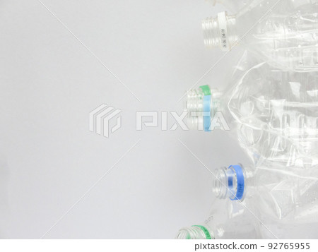 放置在白色繪圖紙右邊緣的多個壓碎塑料瓶容器的特寫和復制空間 放置在白色繪圖紙右邊緣的多個壓碎塑料瓶容器的特寫和復制空間 92765955
