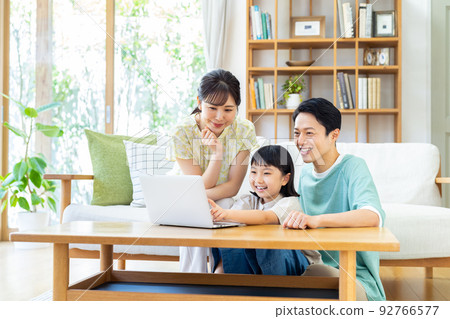Young family looking at a computer in the living room 92766577