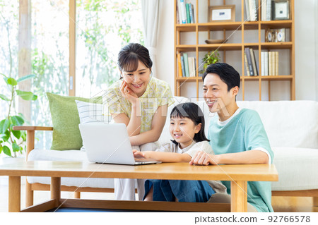 Young family looking at a computer in the living room 92766578