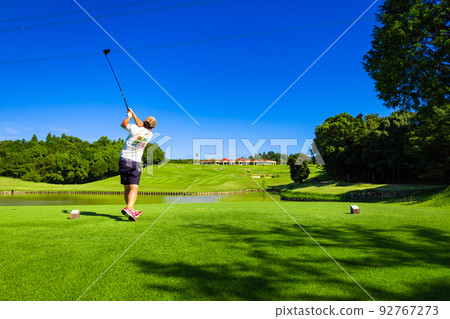 Rear view of a man hitting a driver shot over a pond on the tee ground of a golf course (Kisarazu City, Chiba Prefecture) Rear view of a man hitting a driver shot over a pond on the tee ground of a golf course (Kisarazu City, Chiba Prefecture) 92767273