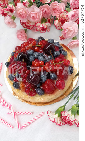 Berry birthday cake. Cheesecake with cherries, raspberries, currants and blueberries. Cake, pink candles and red flowers on a white background. Photo for stories. Berry birthday cake. Cheesecake with cherries, raspberries, currants and blueberries. Cake, pink candles and red flowers on a white background. Photo for stories. 92767754