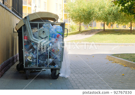 Plastic bottles are collected in a container for sending for recycling. Dumpsters being full with garbage in city. Plastic bottles are collected in a container for sending for recycling. Dumpsters being full with garbage in city. 92767830