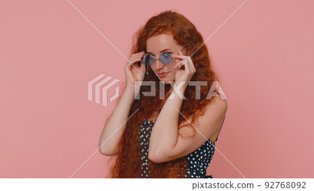 Seductive cheerful ginger stylish girl in dress wearing sunglasses, charming smile on pink wall Seductive cheerful ginger stylish girl in dress wearing sunglasses, charming smile on pink wall 92768092