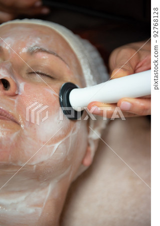 Mature woman with green eyes receiving a facial treatment Mature woman with green eyes receiving a facial treatment 92768128