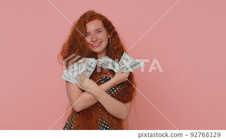 Redhead girl holding cash money dollar celebrate dance, success business career, lottery game winner 92768129