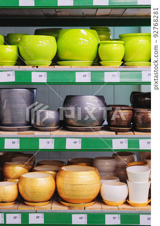Pots for houseplants are sold at the shop. Rows of diversity colored pots for indoor plants on shelves in a supermarket. 92768281