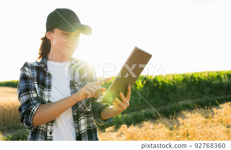 Farmer examines the field of cereals and sends data to the cloud from the tablet. Farmer examines the field of cereals and sends data to the cloud from the tablet. 92768360