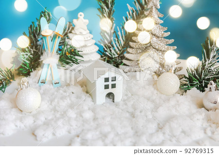 Abstract Advent Christmas Background. Toy model house and winter decorations ornaments on blue background with snow. Christmas with family at home concept 92769315