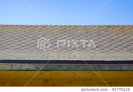 The roof of the wooden house is covered with shingles. Close-up. Roofing The roof of the wooden house is covered with shingles. Close-up. Roofing 92770228