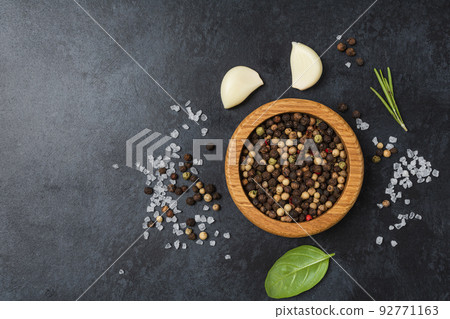 Pepper in wooden bowl on dark black stone table with copy space. Pepper in wooden bowl on dark black stone table with copy space. 92771163