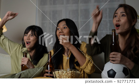 Holiday concept of 4k Resolution. A group of Asian women watching a soccer match broadcast together at home. Fun and exciting leisure activities. Holiday concept of 4k Resolution. A group of Asian women watching a soccer match broadcast together at home. Fun and exciting leisure activities. 92771771