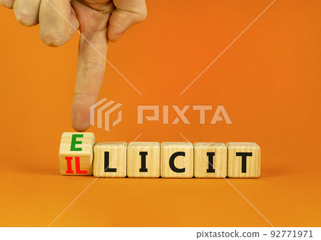 Illicit or elicit symbol. Businessman turns wooden cubes and changes the concept word Illicit to Elicit. Beautiful orange table orange background. Business illicit or elicit concept. Copy space. 92771971