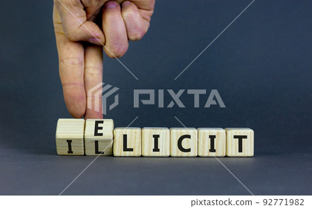 Illicit or elicit symbol. Businessman turns wooden cubes and changes the concept word Illicit to Elicit. Beautiful grey table grey background. Business illicit or elicit concept. Copy space. 92771982