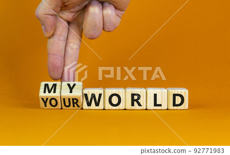 My or your world symbol. Businessman turns wooden cubes and changes words 'your world' to 'my world'. Beautiful orange table, orange background, copy space. Business and my or your world concept. 92771983
