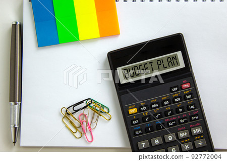Calculator with inscription 'budget plan', white note, colored paper, paper clips, pen. Business concept. Beautiful white background, copy space. Calculator with inscription 'budget plan', white note, colored paper, paper clips, pen. Business concept. Beautiful white background, copy space. 92772004