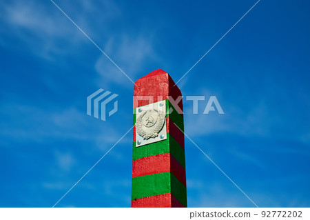 Russian border post with coat of arms against a blue cloudy sky 92772202