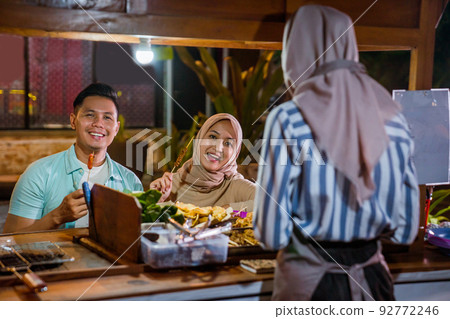 muslim couple enjoying having dinner out at traditional food market muslim couple enjoying having dinner out at traditional food market 92772246